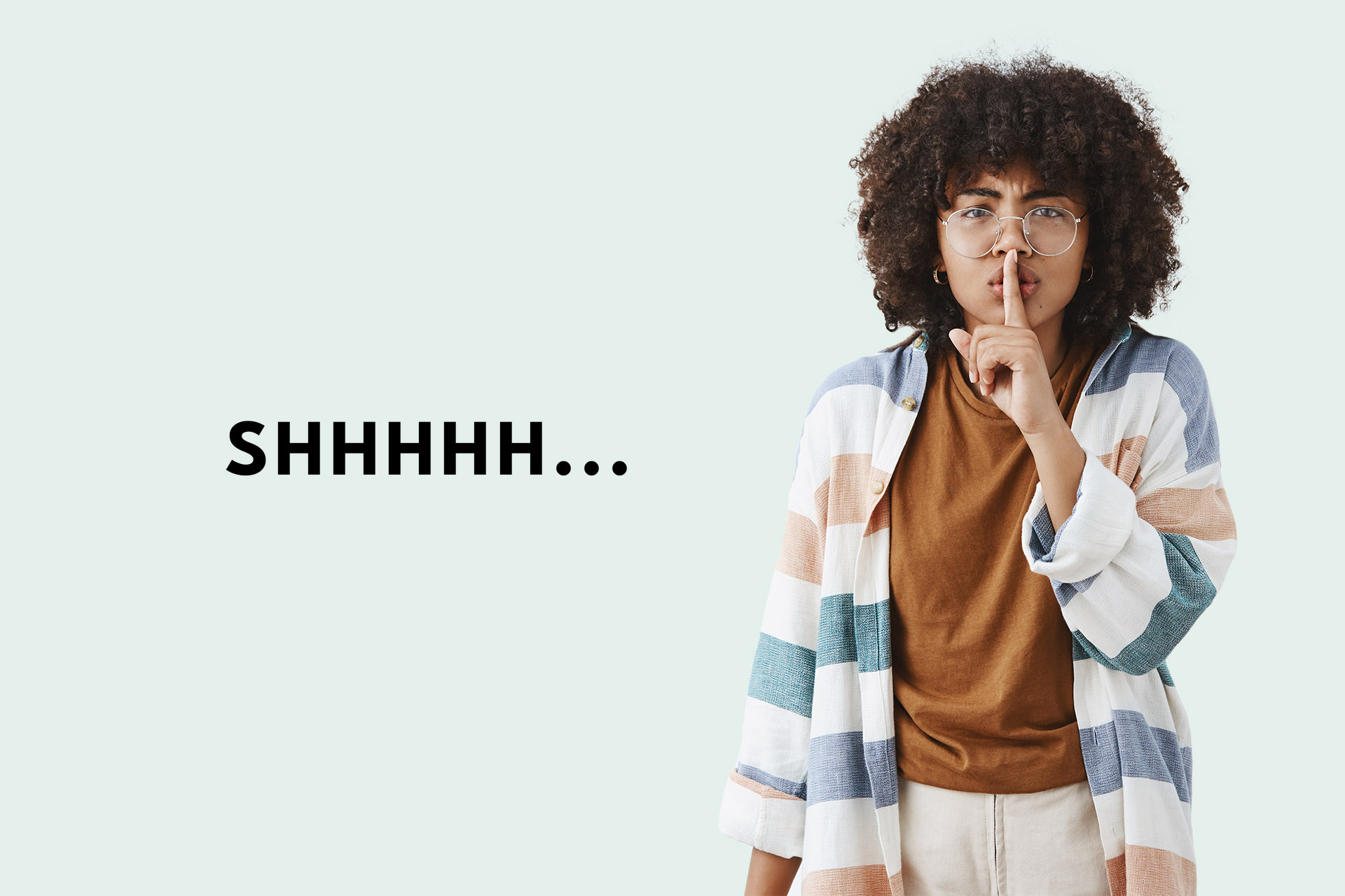 Waist-up shot of serious displeased african american female tutor with afro hairstyle in trendy clothes saying shh showing shush gesture with index finger over mouth demanding silence during lesson. Copy space